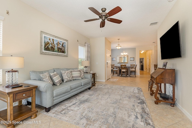 living room featuring light tile patterned flooring and ceiling fan with notable chandelier