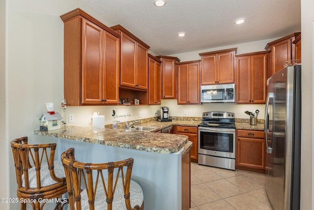 kitchen featuring kitchen peninsula, light stone counters, light tile patterned floors, and stainless steel appliances