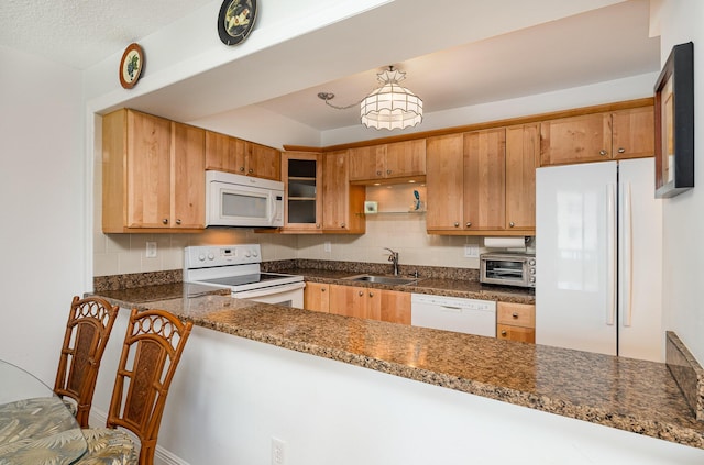 kitchen featuring kitchen peninsula, white appliances, sink, and dark stone counters