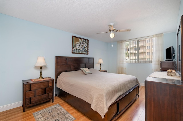 bedroom featuring ceiling fan, a textured ceiling, and light hardwood / wood-style flooring