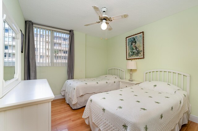 bedroom featuring ceiling fan, light hardwood / wood-style flooring, and a textured ceiling