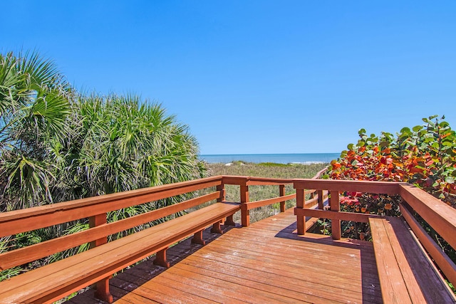 wooden terrace featuring a water view and a beach view