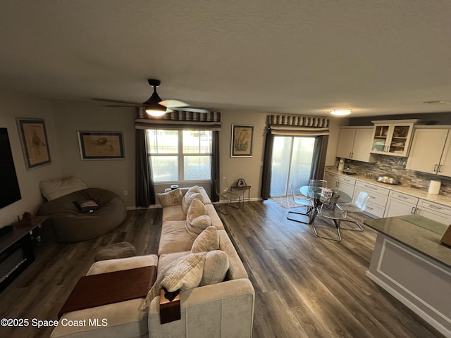 living room featuring ceiling fan and dark wood-type flooring