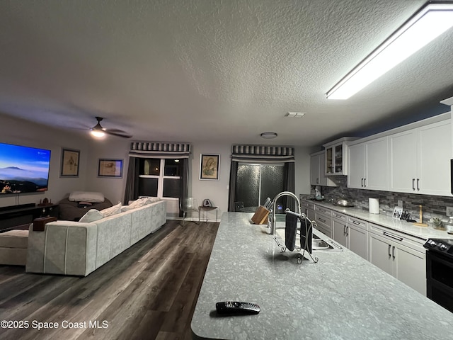 kitchen featuring backsplash, white cabinets, sink, range with electric stovetop, and a textured ceiling