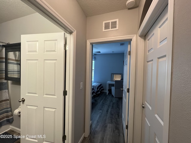 hallway with a textured ceiling and dark wood-type flooring