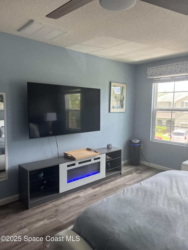 bedroom featuring hardwood / wood-style flooring, ceiling fan, and a textured ceiling