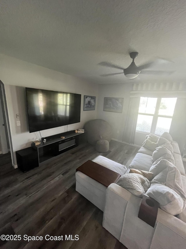 living room featuring ceiling fan, dark hardwood / wood-style floors, and a textured ceiling