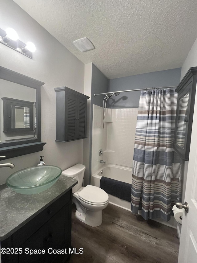 full bathroom featuring a textured ceiling, vanity, hardwood / wood-style flooring, shower / bathtub combination with curtain, and toilet