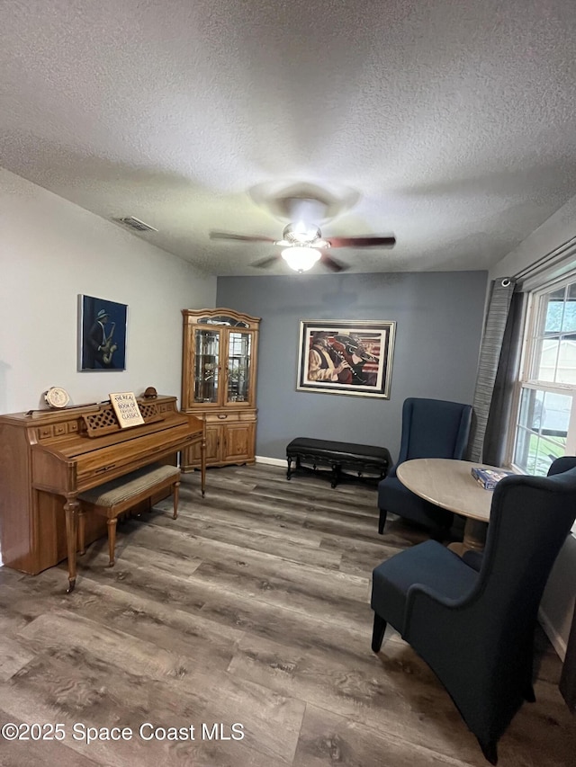 sitting room with a textured ceiling, hardwood / wood-style flooring, and ceiling fan