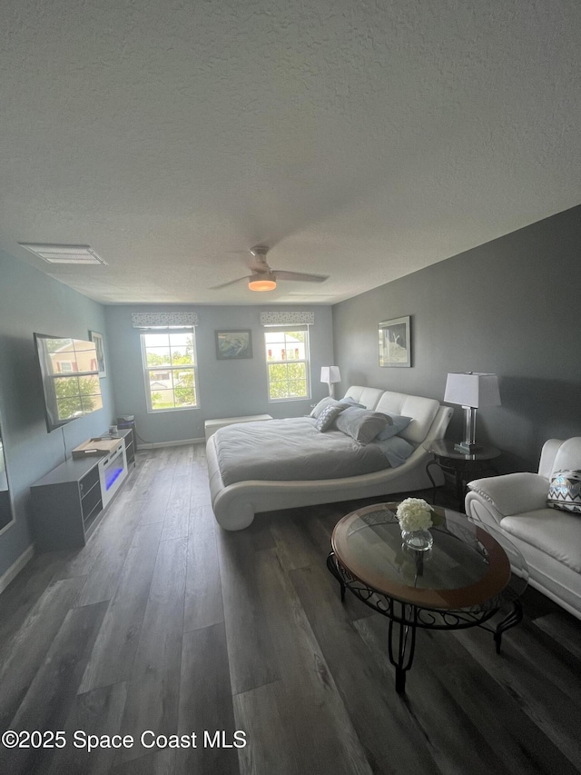 bedroom with ceiling fan, dark hardwood / wood-style floors, and a textured ceiling