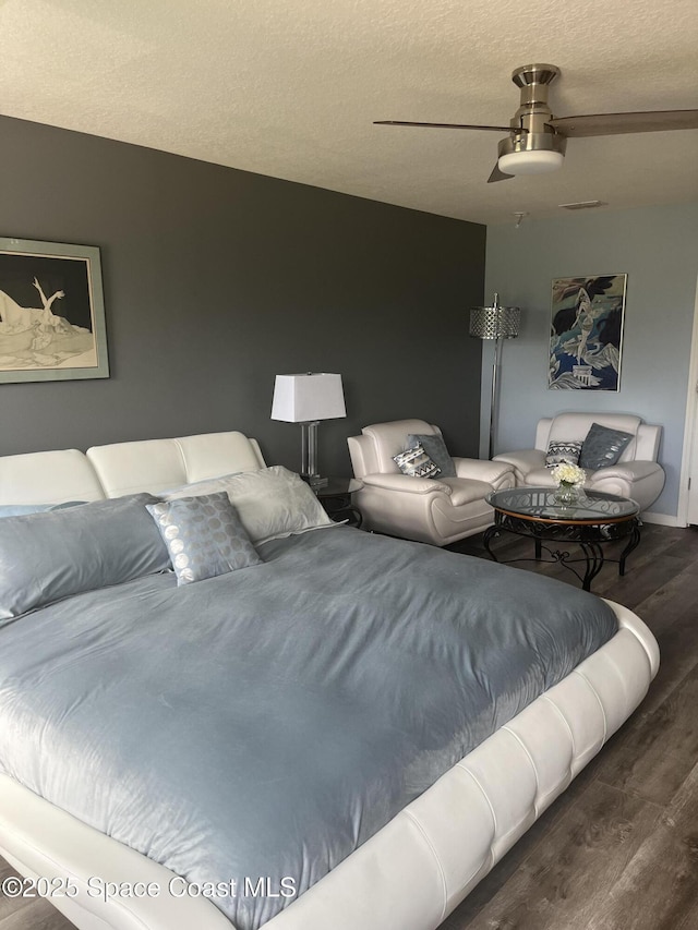 bedroom with a textured ceiling, ceiling fan, and dark hardwood / wood-style floors