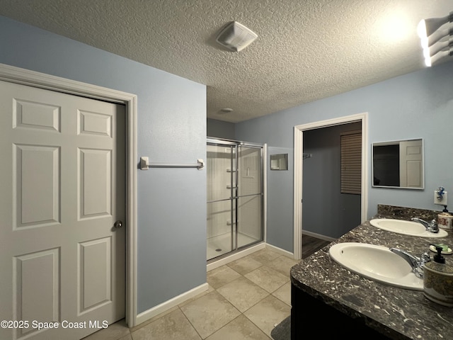 bathroom with tile patterned flooring, vanity, a textured ceiling, and walk in shower