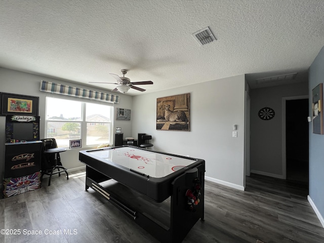 recreation room featuring ceiling fan, dark hardwood / wood-style floors, and a textured ceiling