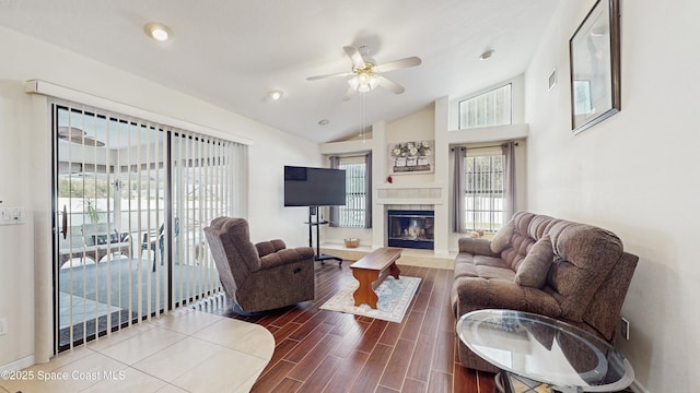 living room featuring ceiling fan, lofted ceiling, and a tiled fireplace