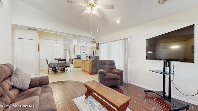 living room with ceiling fan with notable chandelier and lofted ceiling