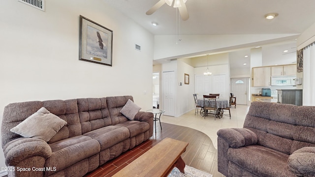 living room featuring ceiling fan with notable chandelier and lofted ceiling