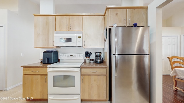 kitchen featuring light brown cabinetry and white appliances