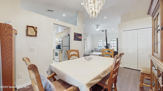 dining space with dark wood-type flooring and ceiling fan with notable chandelier