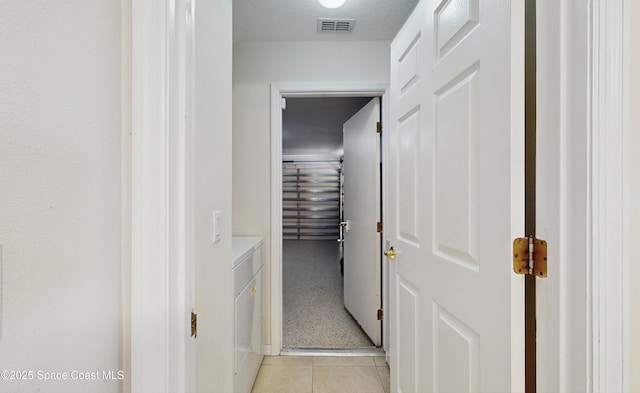 hall with washer and dryer and light tile patterned flooring