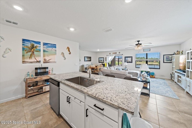 kitchen featuring white cabinets, a center island with sink, sink, stainless steel dishwasher, and ceiling fan