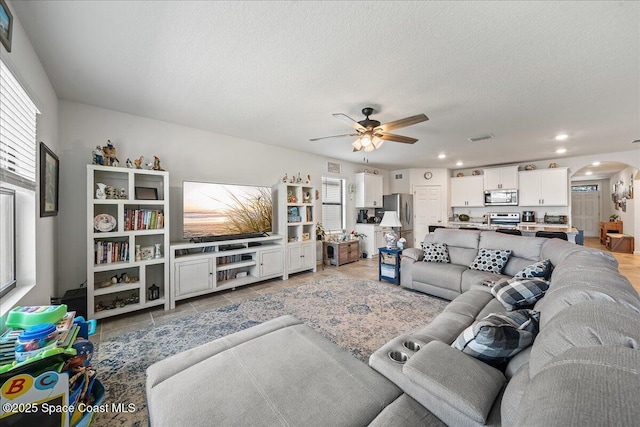 tiled living room with a textured ceiling and ceiling fan