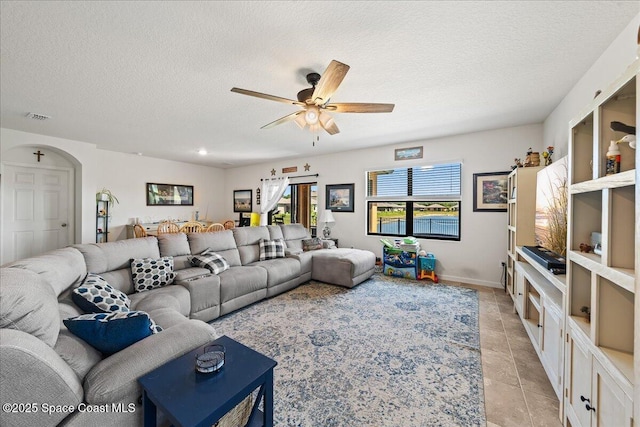 tiled living room featuring ceiling fan and a textured ceiling