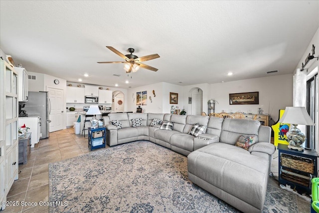 living room with ceiling fan, light tile patterned flooring, and a textured ceiling