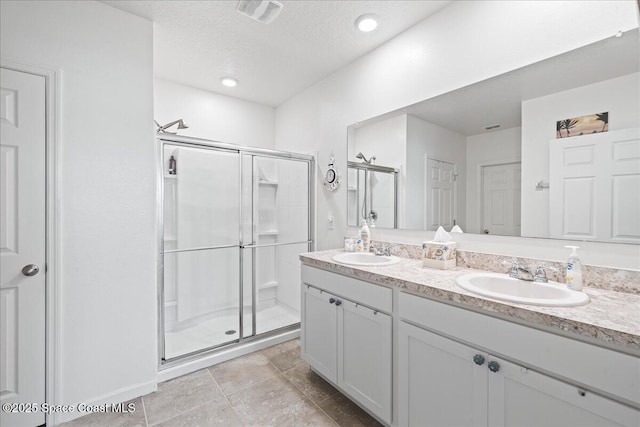 bathroom with vanity, a textured ceiling, and a shower with shower door