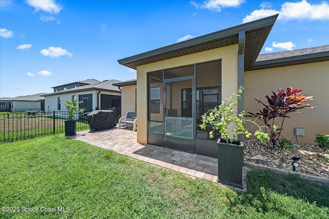 rear view of house featuring a lawn and a sunroom