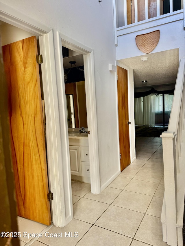 corridor featuring sink and light tile patterned flooring