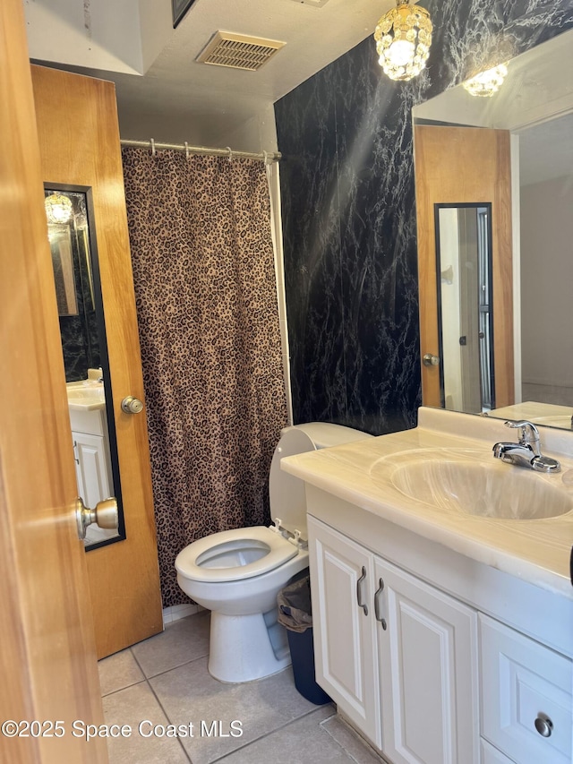 bathroom featuring tile patterned flooring, vanity, toilet, and walk in shower