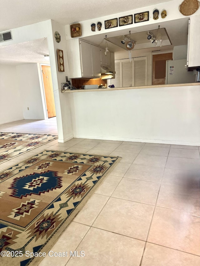 interior space with light tile patterned flooring, a textured ceiling, and white refrigerator