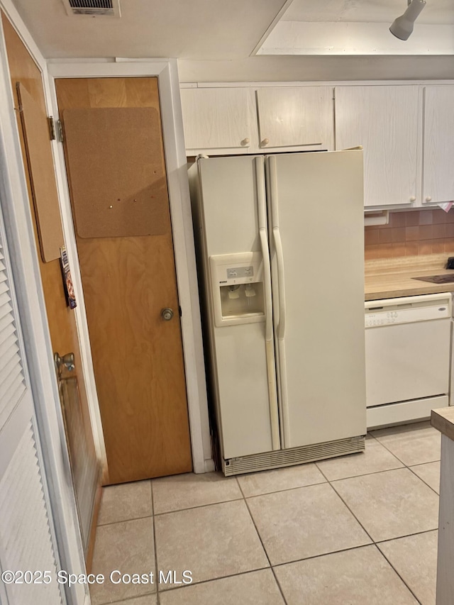 kitchen featuring light tile patterned floors, white appliances, and tasteful backsplash