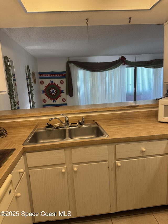 kitchen with sink, light tile patterned flooring, and a textured ceiling