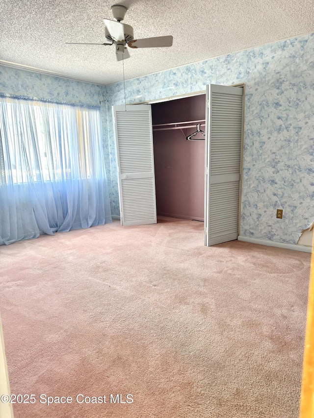 unfurnished bedroom featuring carpet flooring, ceiling fan, a textured ceiling, and a closet