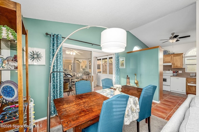 tiled dining space featuring ceiling fan and lofted ceiling