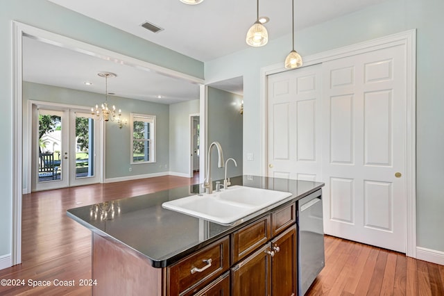 kitchen with dishwasher, decorative light fixtures, french doors, sink, and a kitchen island with sink