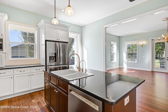 kitchen with a kitchen island with sink, backsplash, appliances with stainless steel finishes, and white cabinetry