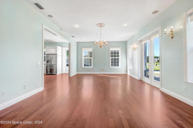 unfurnished living room with dark hardwood / wood-style flooring and a chandelier