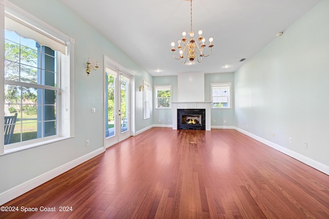 unfurnished living room with wood-type flooring and an inviting chandelier