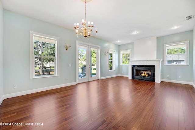 unfurnished living room with a chandelier, dark hardwood / wood-style flooring, and a tiled fireplace