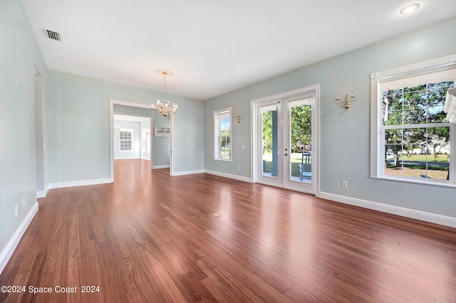 spare room featuring dark hardwood / wood-style flooring, french doors, and a notable chandelier