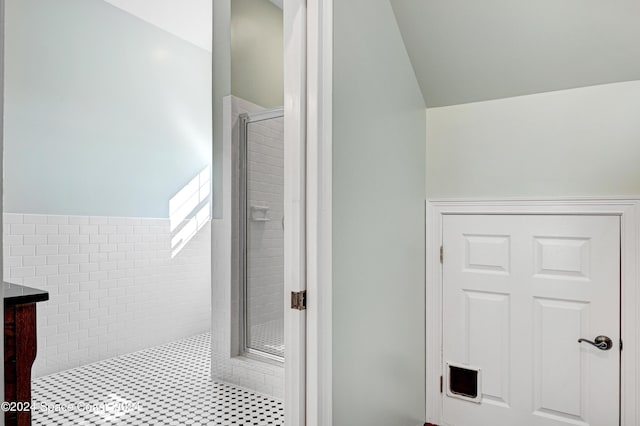 bathroom featuring a shower with shower door, vanity, and lofted ceiling