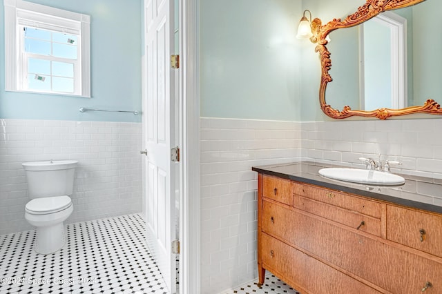 bathroom with toilet, tile patterned flooring, tile walls, and vanity