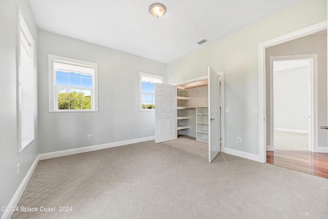 unfurnished bedroom featuring light colored carpet, a closet, and a spacious closet