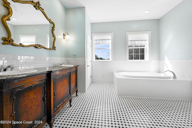 bathroom with vanity, tile walls, and a tub