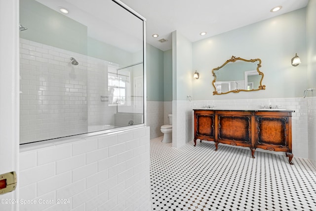 bathroom featuring tile patterned floors, vanity, tile walls, toilet, and tiled shower