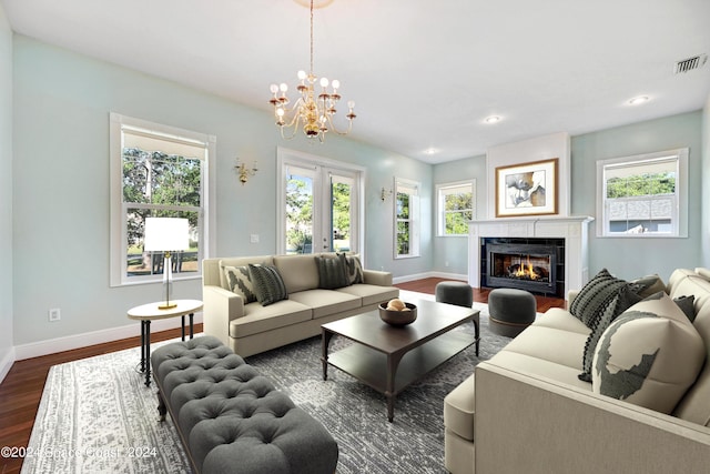 living room featuring french doors, a fireplace, a chandelier, and dark hardwood / wood-style floors