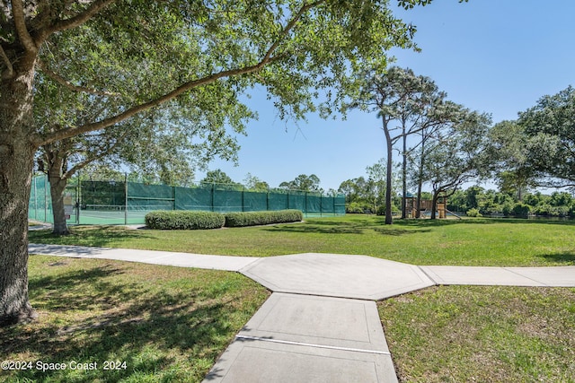 view of community featuring tennis court, a yard, and a playground