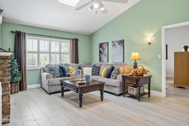 living room featuring lofted ceiling with skylight, light hardwood / wood-style flooring, ceiling fan, and a textured ceiling